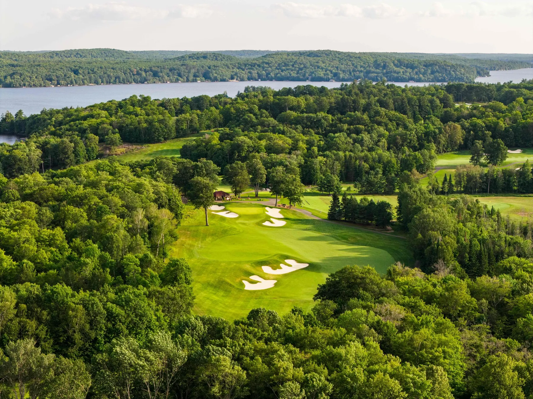 Aerial of a fairway and bunkers leading toward the clubhouse, with the lake behind