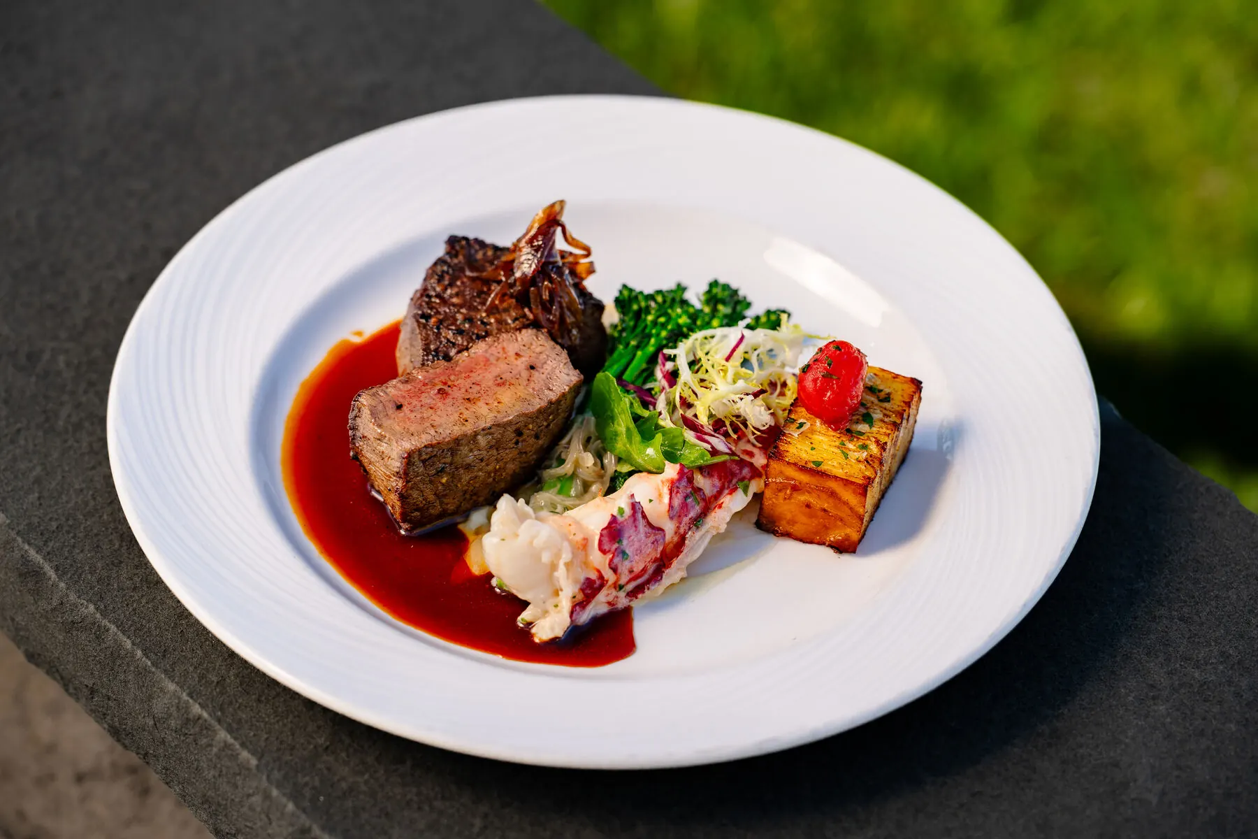 Plated steak and lobster dish at Huntington Crescent Club