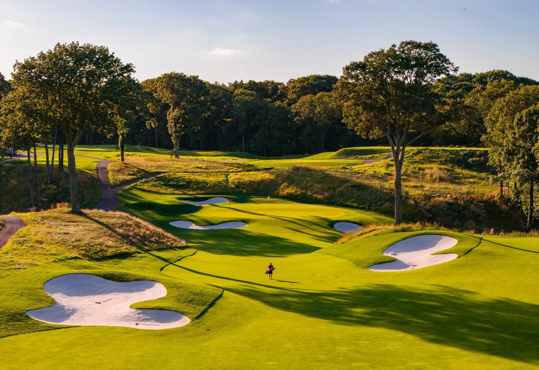 Golfer walking the green among bunkers at Huntington Crescent Club