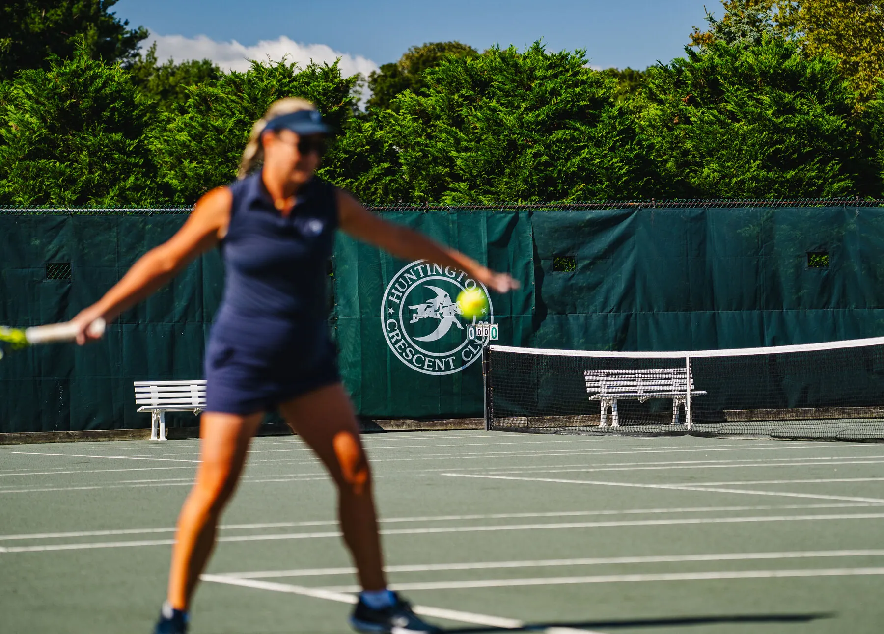 Tennis player in action on the grass court at Huntington Crescent Club