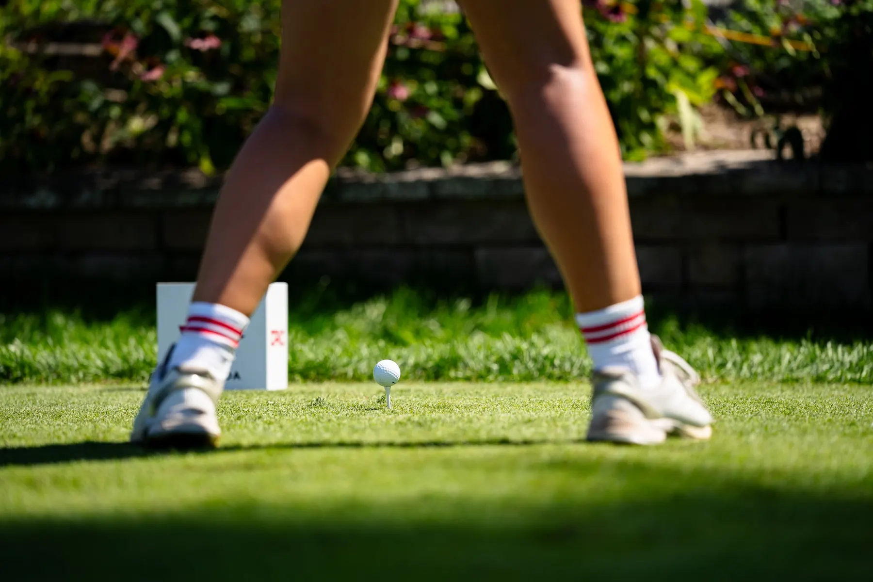 Close-up of a player's stance over a teed ball